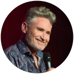 Dave Hughes smiling with a microphone in his hand